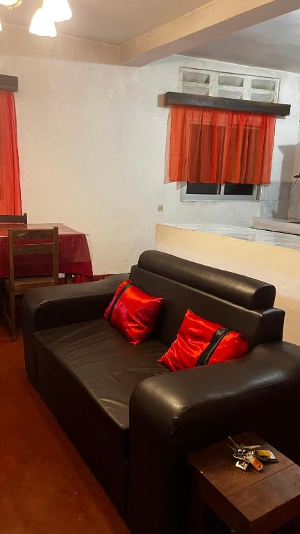 a living room with a black couch and red pillows at Villa Cali PASO in Sambava