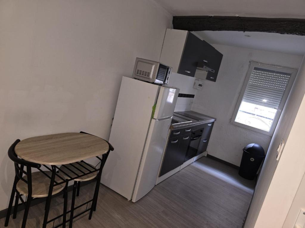 a small kitchen with a small table and a refrigerator at gite atoma in Rivesaltes