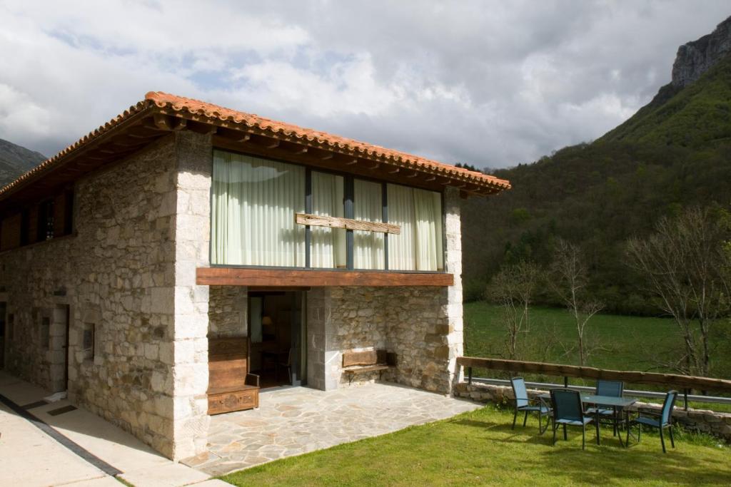 une maison en pierre avec une table et des chaises devant elle dans l'établissement Apartamentos Rurales El Lleron, à Caso