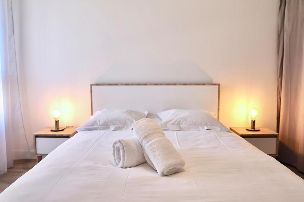 een wit bed met twee lampen op twee tafels bij La Perdrix in Sainte-Adresse