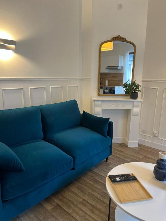 un canapé bleu dans un salon avec une table et un miroir dans l'établissement Le petit Gambon - 4 personnes - Place de parking privé, à Bourges