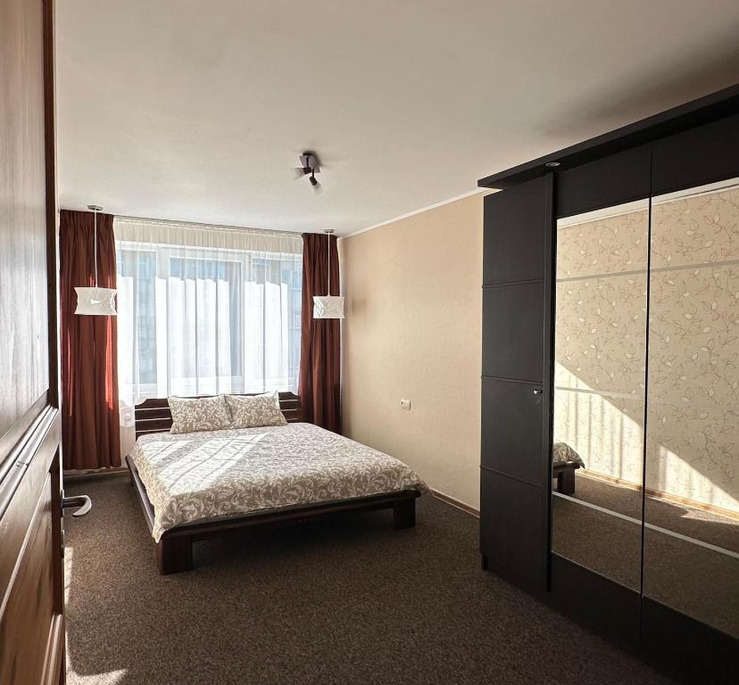 a bedroom with a bed and a large window at Evergreen City Apartment in Valmiera