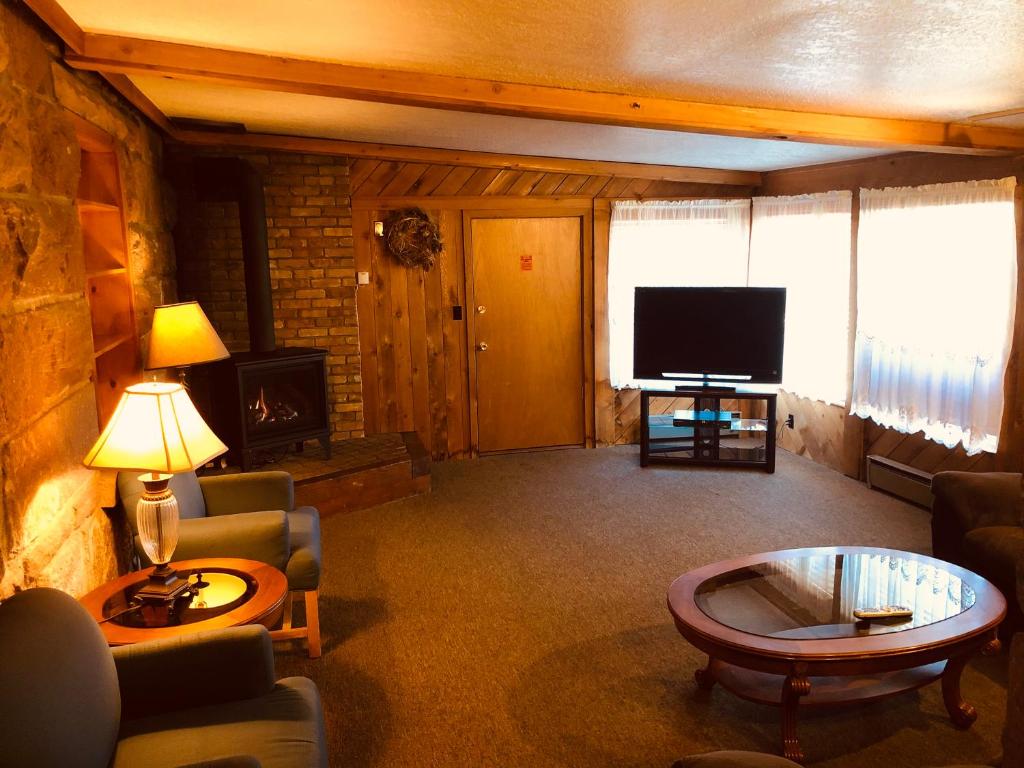 a living room with a tv and a couch and a table at Glenwood Springs Cedar Lodge in Glenwood Springs