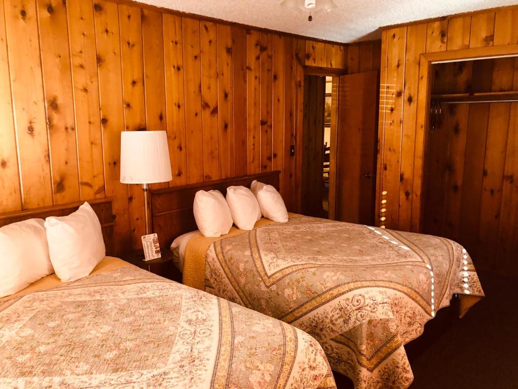 two beds in a room with wooden walls at Glenwood Springs Cedar Lodge in Glenwood Springs