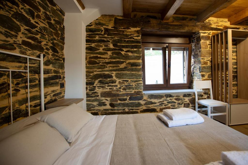 a bedroom with a bed in a stone wall at Refuxio de Lamas in Becerreá