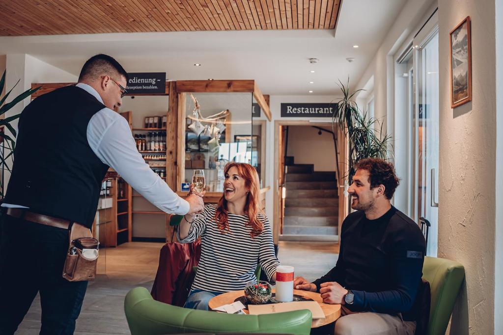 a man giving a woman a glass of wine at Alpengasthof Hörnlepass in Riezlern
