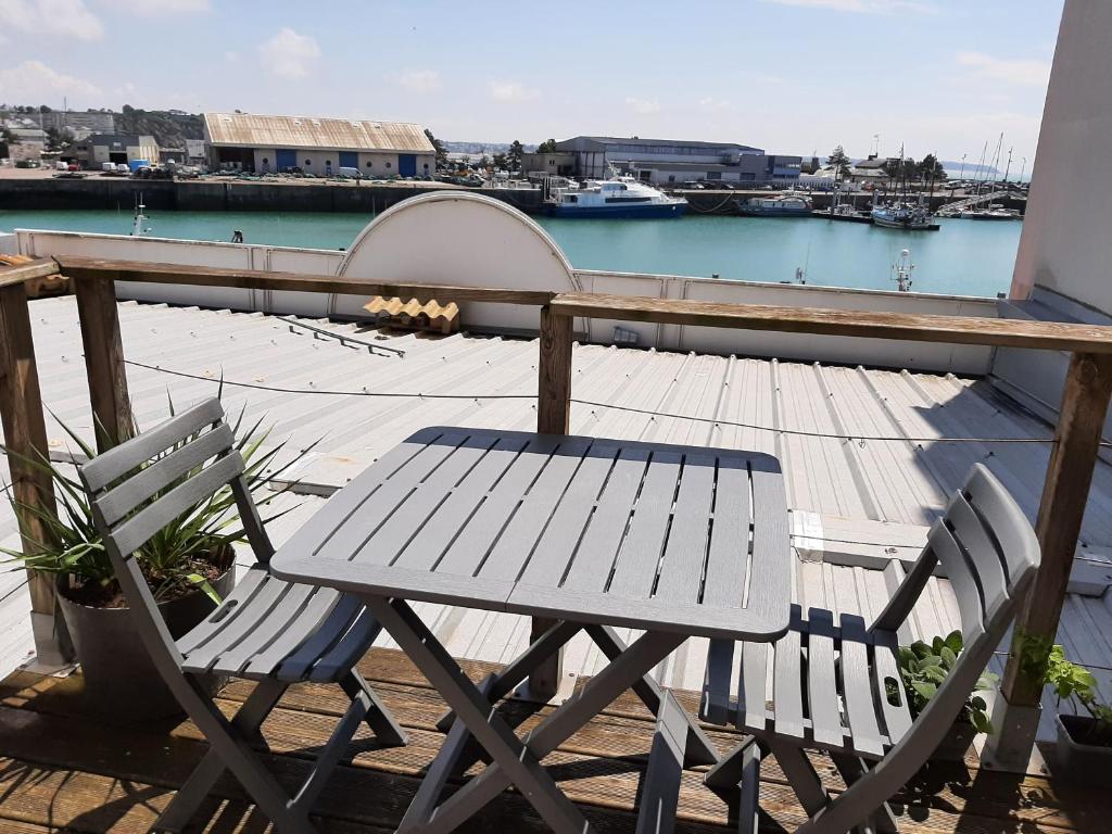 - une table et des chaises en bois sur un balcon avec un port dans l'établissement La Cabine, à Granville