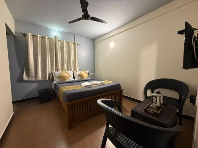 a bedroom with a bed with a fan and a table at Humming Bird suite in Kotagiri
