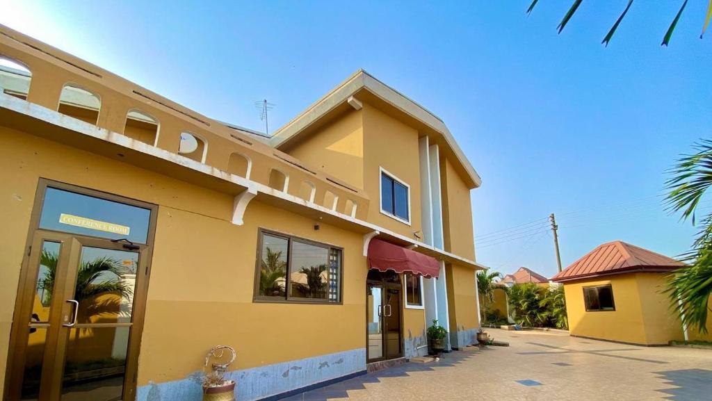 a yellow building with a fire hydrant in front of it at Lavimac Royal Hotel in Kumasi