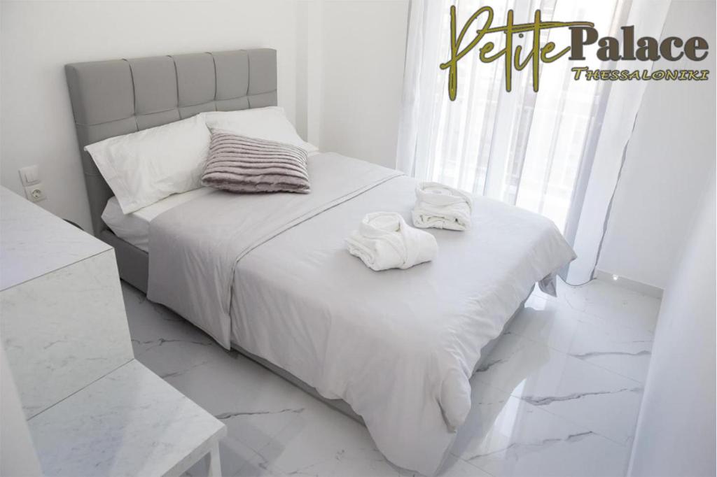 a white bedroom with a bed with towels on it at Petite Palace Aristotelous 7 in Thessaloniki