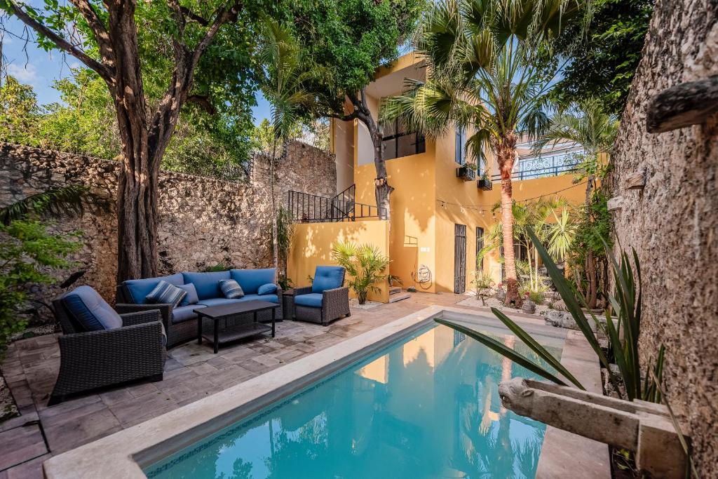 a swimming pool with furniture next to a house at Casa La Escondida in Mérida