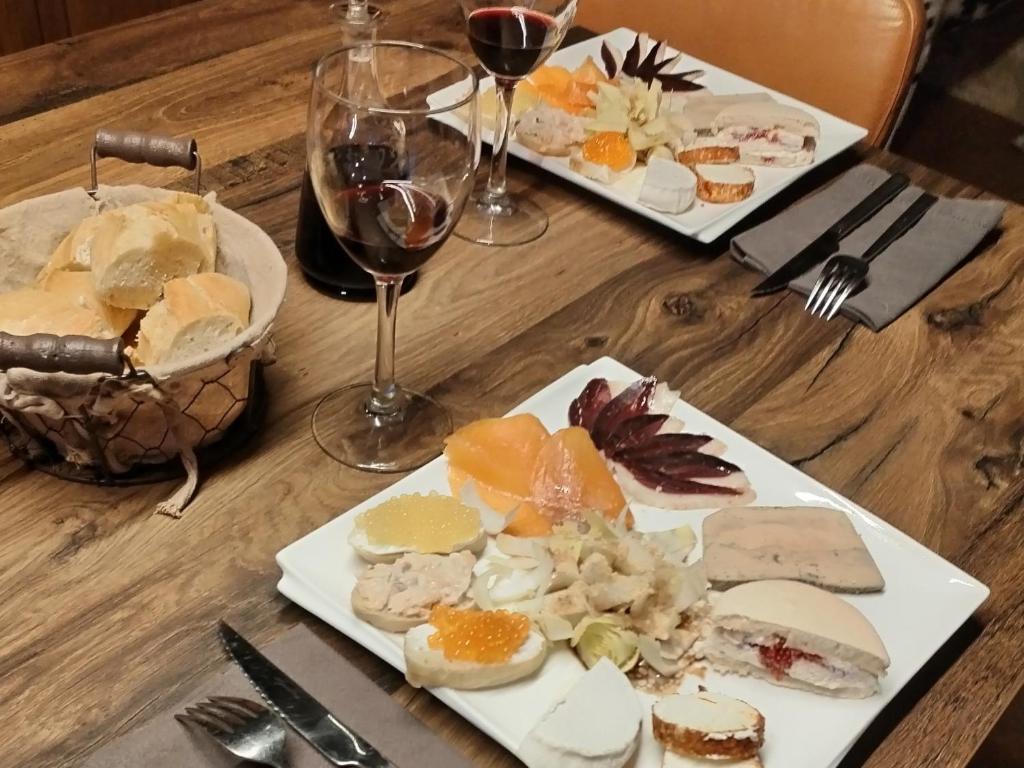 a table with two plates of food and glasses of wine at Chambre d'hôtes de la dame blanche in Borrèze