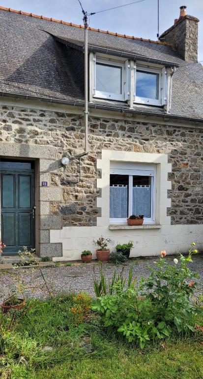 une maison en briques avec deux fenêtres et quelques plantes dans l'établissement L'Agapanthe, Gîte au coeur de la Baie de Saint Brieuc, à Hillion