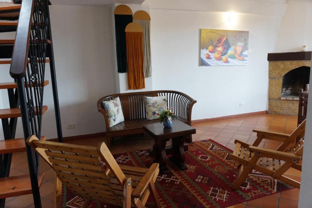 een woonkamer met een tafel, stoelen en een open haard bij Hermoso Apartamento Faros de la Villa a 4 calles de la Plaza in Villa de Leyva