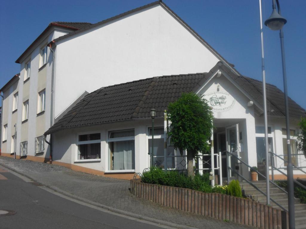 ein weißes Gebäude mit schwarzem Dach auf einer Straße in der Unterkunft Landhaus Schaaf in Runkel