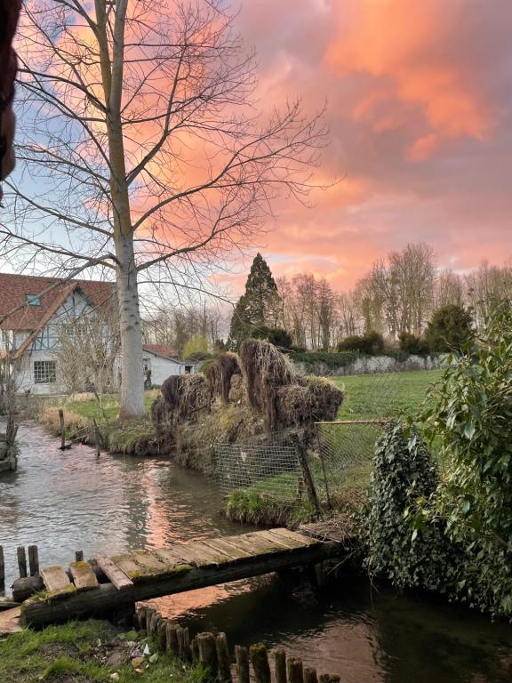 un pont sur une rivière avec une maison en arrière-plan dans l'établissement Gîte pieds dans l Epte prêt de Giverny, à Gasny