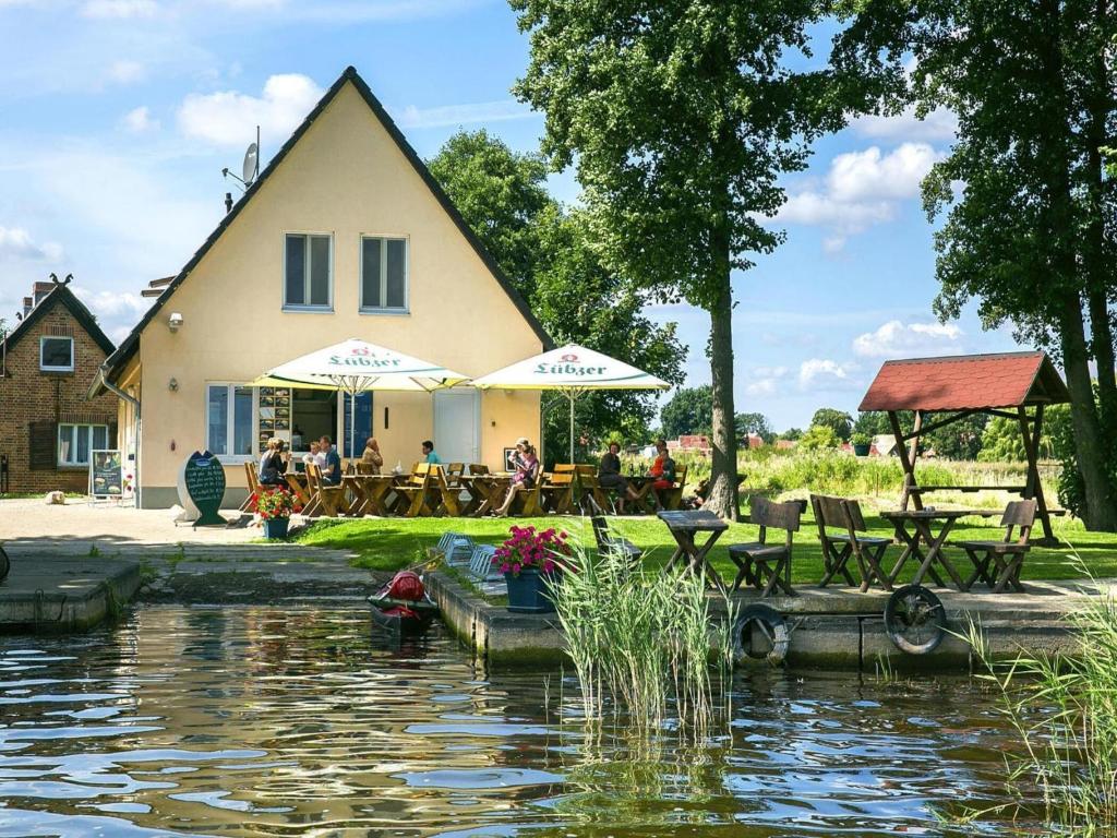 a building with people sitting at tables near a pond at Ferienwohnung auf dem Fischerhof, Vipperow in Vipperow