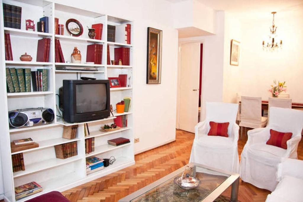 sala de estar con TV y estanterías blancas en Mena House en Recoleta 3 Bed 2 Bath - Piso Alto en Buenos Aires