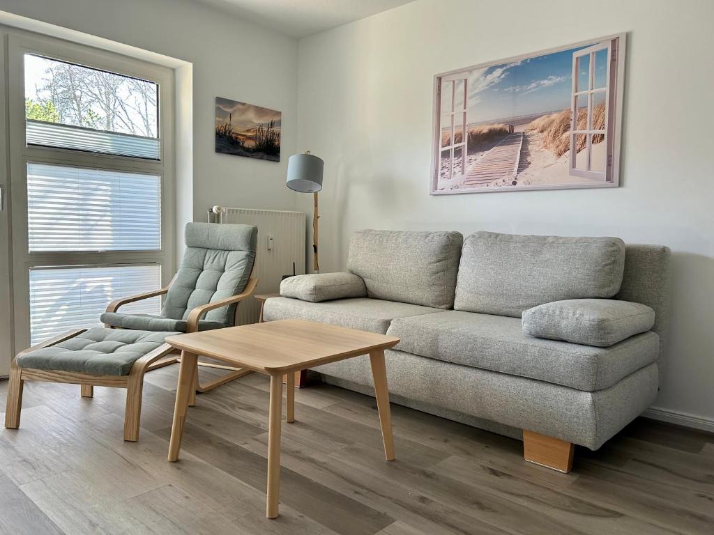 Una sala de estar con un sofá, una mesa y una silla. en Ferienwohnung Bullerby-Büsum, ehemals Holländerei, en Büsum