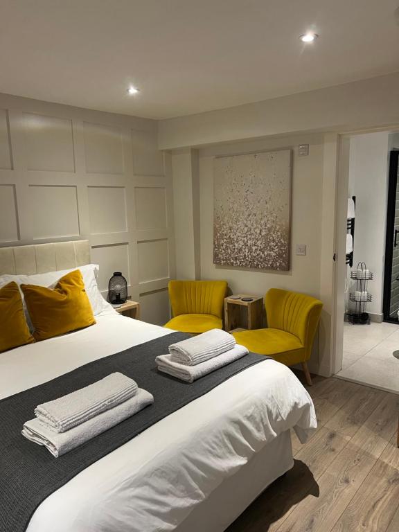 a bedroom with a large bed with two yellow chairs at Lower Greenbank Guest Suite in Oban