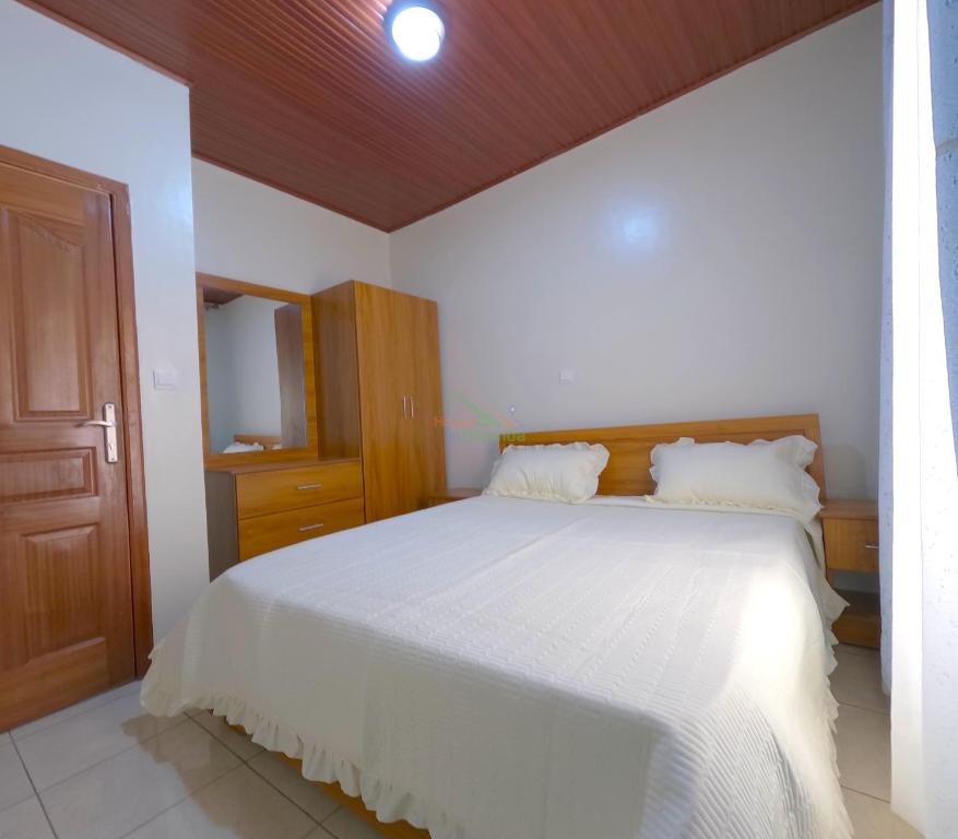 a bedroom with a white bed and a wooden ceiling at Home2home in Kigali