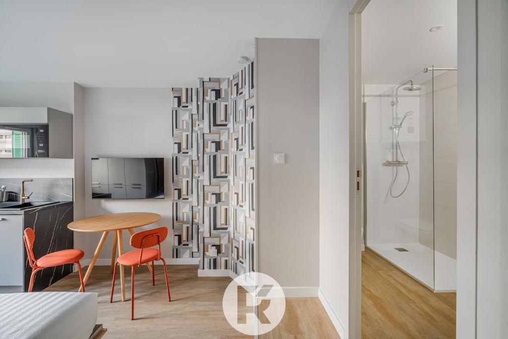 Cette chambre comprend une table, des chaises et une douche. dans l'établissement R'Apparts Latelier D'exception S2, à Grenoble