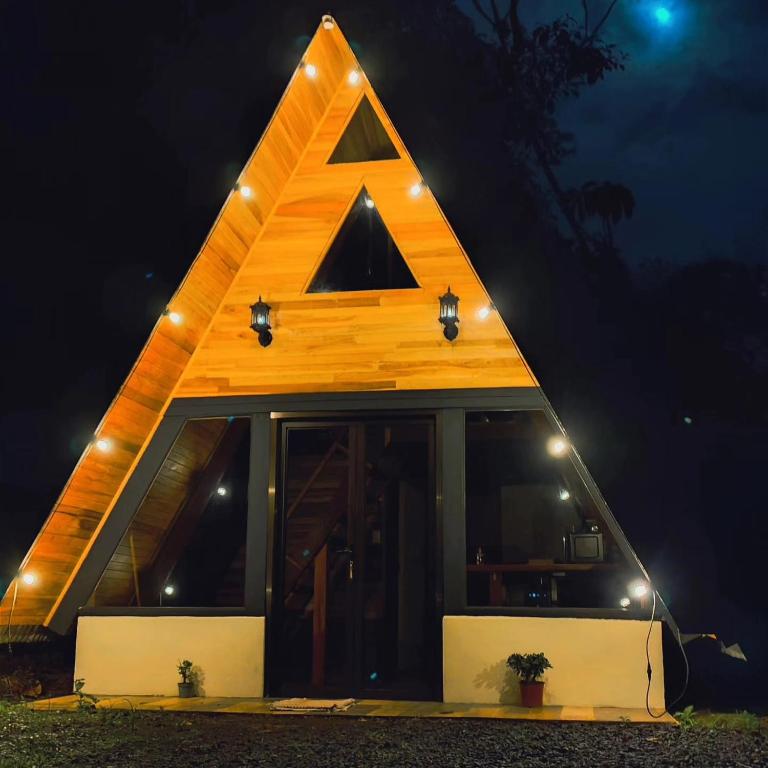 a triangle shaped house with lights on it at night at Pozas y Cascadas La Presa in Río Cuarto