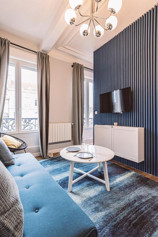 un salon avec un canapé bleu et une table dans l'établissement Le Méditerranéen, face à la Cathédrale - 2D, à Reims