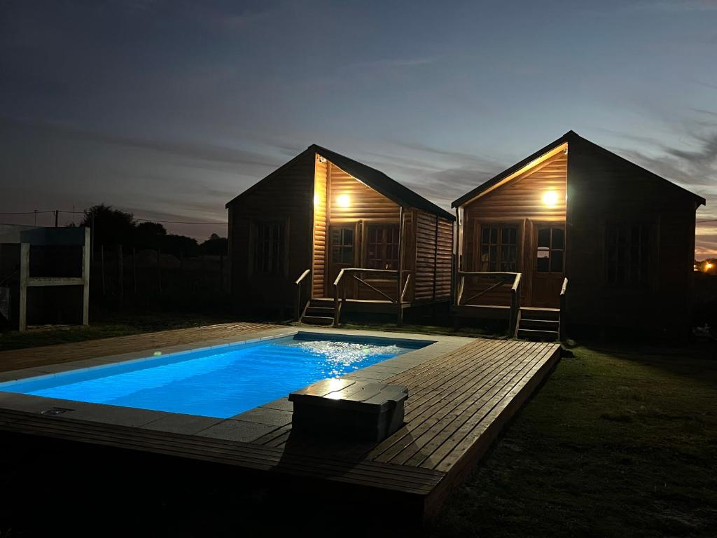 a tiny house with a swimming pool at night at Complejo de cabañas El Mangrullo in Larroque