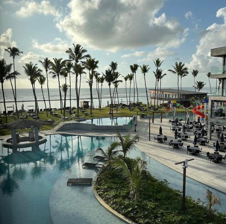 a resort with a swimming pool and palm trees and the ocean at Porto Alto Gav Resorts in Porto De Galinhas