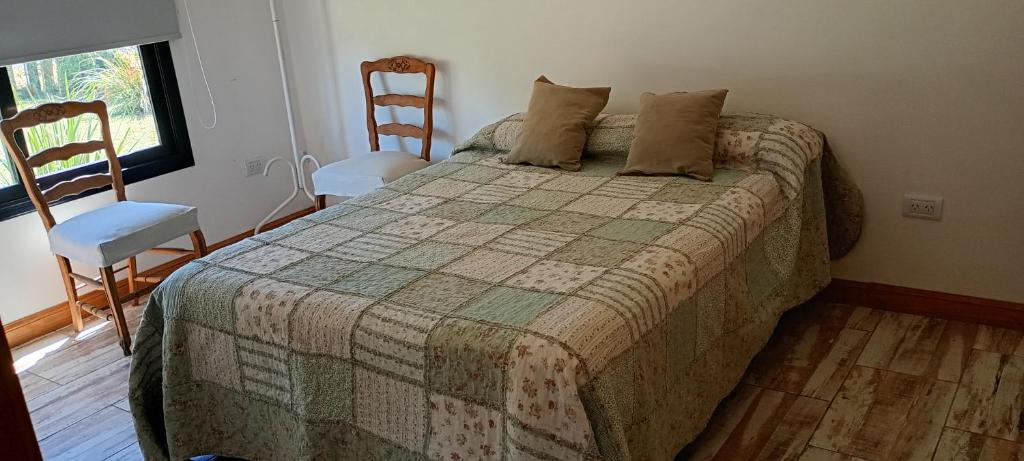 1 Schlafzimmer mit einem Bett mit 2 Stühlen und einem Fenster in der Unterkunft Quinta Ensenada in Bragado