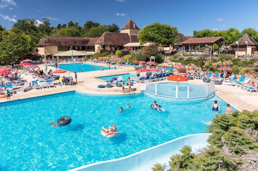 a pool at a resort with people in the water at Camping Saint Avit Loisirs in Journiac