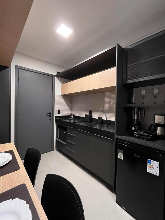 a kitchen with black cabinets and a table with chairs at Flat aconchegante à 300m do mar! in Cabedelo