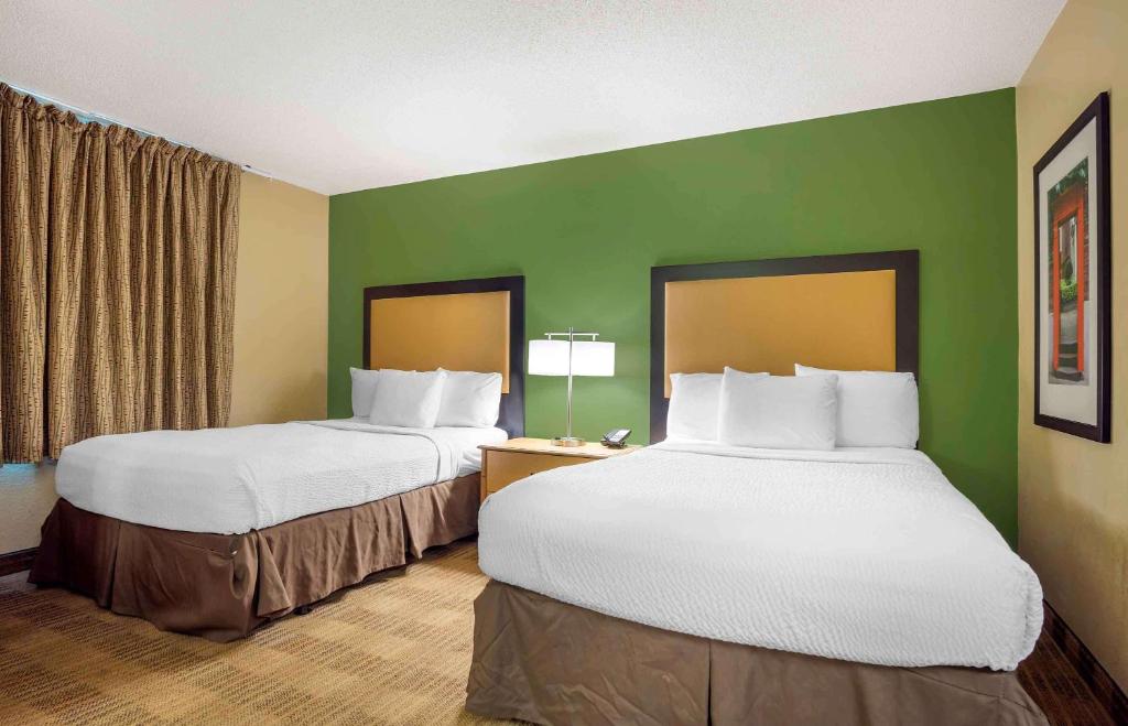 two beds in a hotel room with green walls at Extended Stay America Select Suites - Orlando - Lake Mary - 1040 Greenwood Blvd in Lake Mary