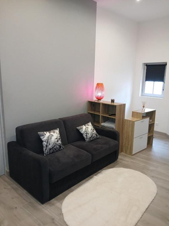 - un salon avec un canapé noir et un bureau dans l'établissement Appartement plein pied, à Dijon