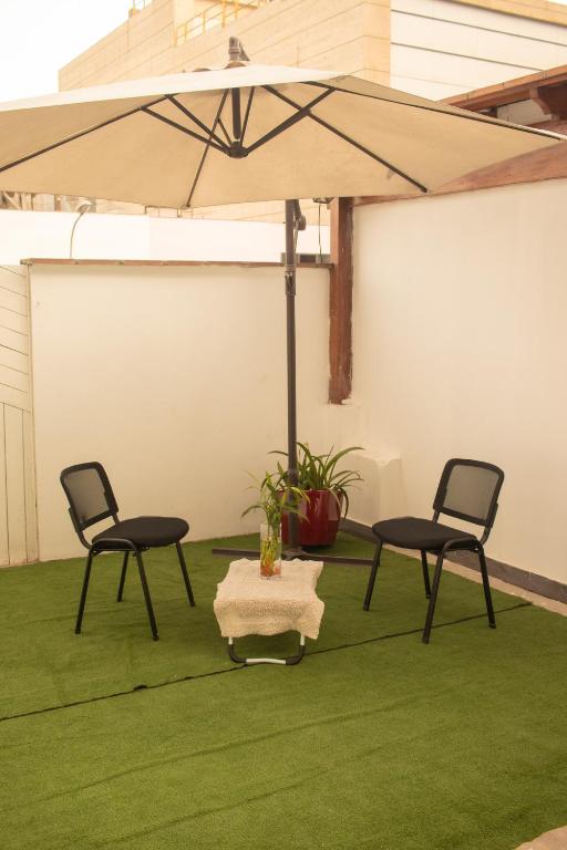 un patio con due sedie e un ombrellone di Gutierrez Hostel a Lima