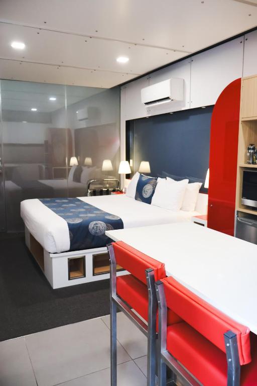 a hotel room with two beds and a red bench at Stay Motel - Formerly Room Motels Gympie in Gympie