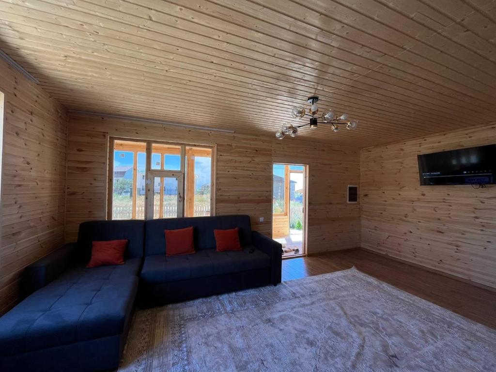 a living room with a blue couch and a tv at WooD_House_Issyk-Kul in Bosteri