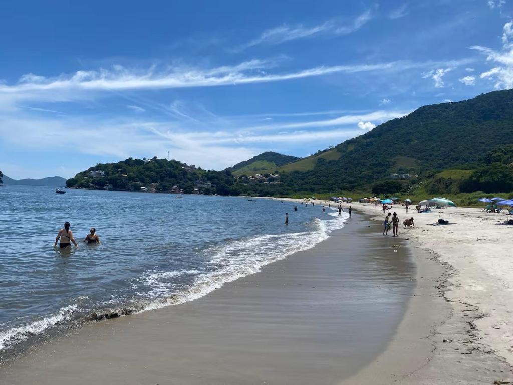 a group of people in the water on a beach at Casa em Condomínio em Mangaratiba in Mangaratiba