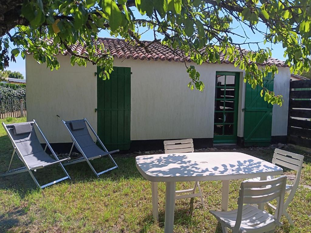 2 chaises, une table, une table et des chaises sous un arbre dans l'établissement Petite Maison à 500m de la Plage, 300m du Centre – Idéale pour Séjour à Pied! - FR-1-476-5, à La Faute-sur-Mer