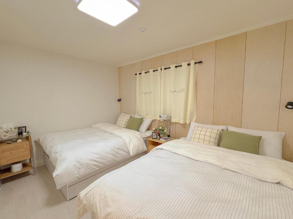 a bedroom with two beds and a table and a window at Doors Seongsu in Seoul