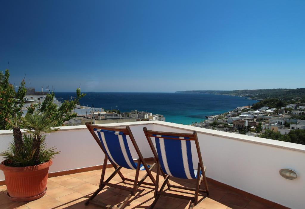 Duas cadeiras numa varanda com vista para o oceano em Hotel Degli Ulivi em Castro di Lecce