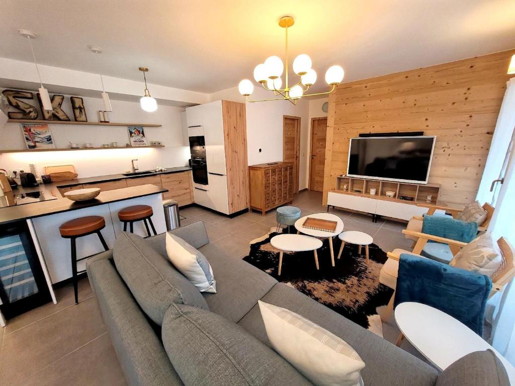 Il comprend un salon avec un canapé gris et une cuisine. dans l'établissement Les Gets - Appartement moderne avec grande terrasse, parking et 2 chambres - FR-1-598-185, aux Gets
