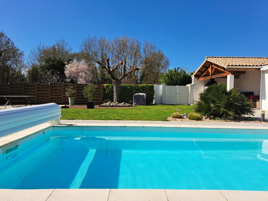 une piscine bleue devant une maison dans l'établissement Chambre d hôte la rivière 45m2 jardin et piscine, à Aigrefeuille-dʼAunis