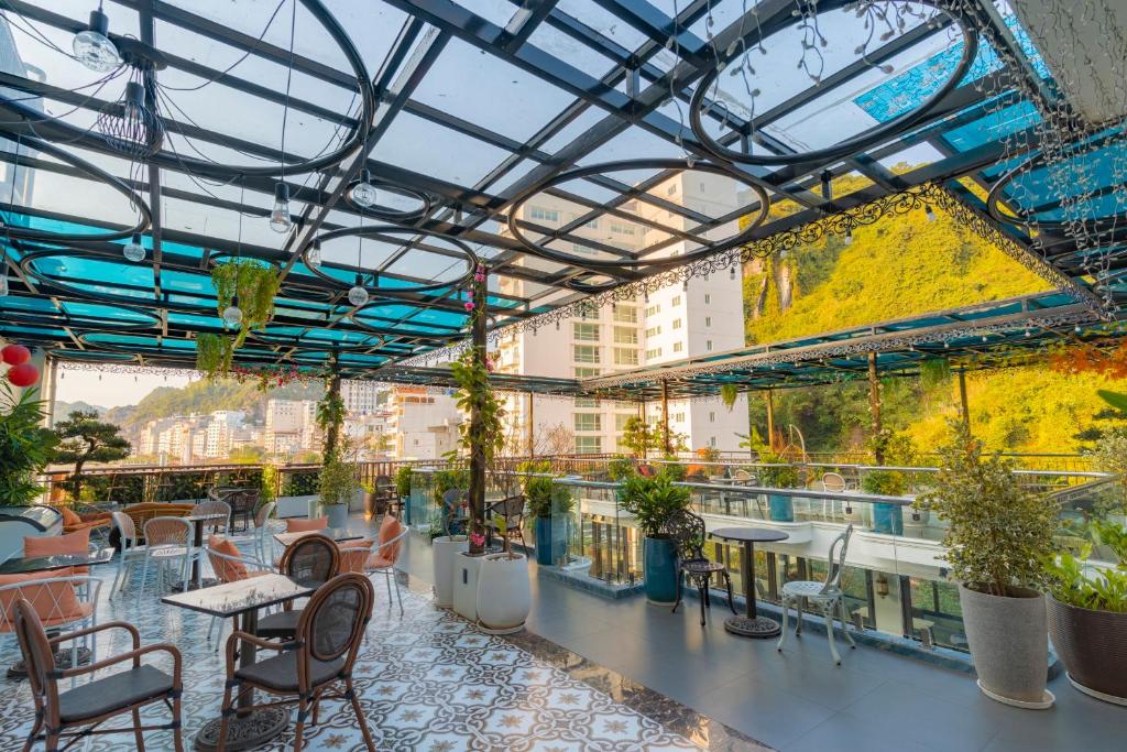 a rooftop patio with tables and chairs and plants at Roza Luxury Cat Ba - Cave hotel, Swimming Pool & Rooftop in Cat Ba