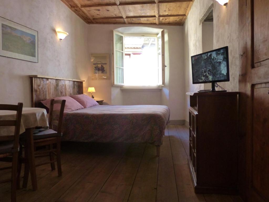 a bedroom with a bed and a table and a window at B&B Ploncher in Chiavenna