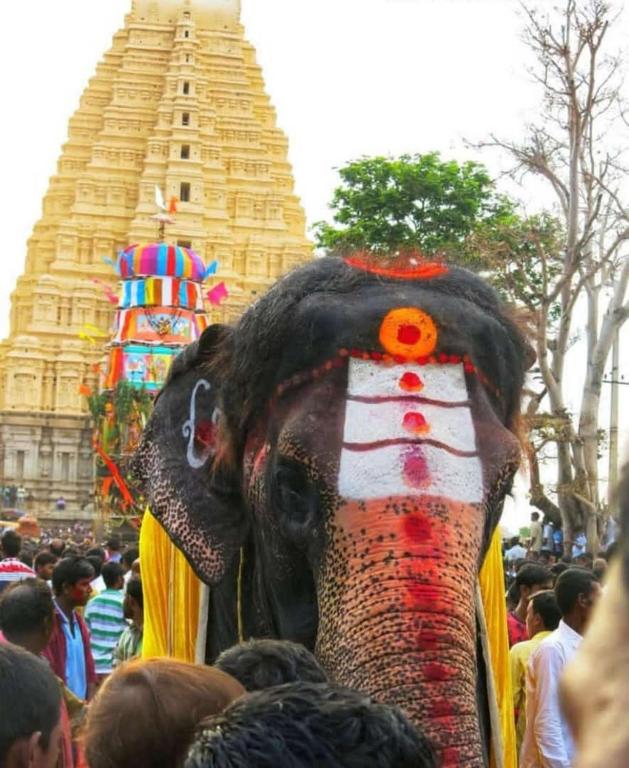 an elephant with a painted face standing in a crowd at Mamatha Guest inn in Hampi