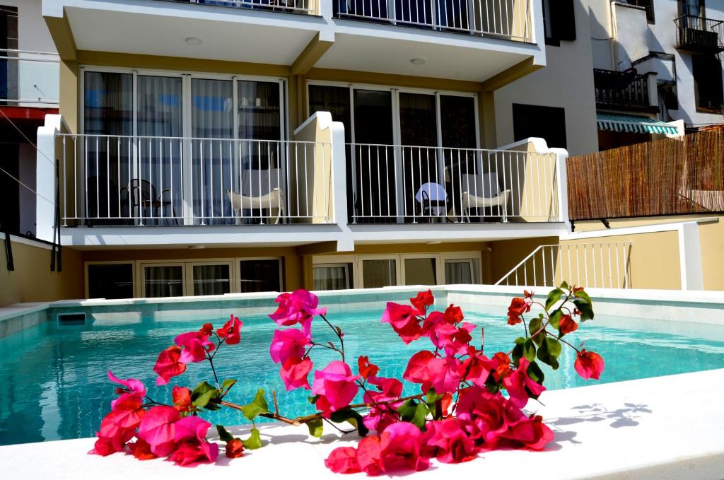 ein Pool mit rosa Blumen vor einem Gebäude in der Unterkunft VILA TOCA by brugrani in Funchal