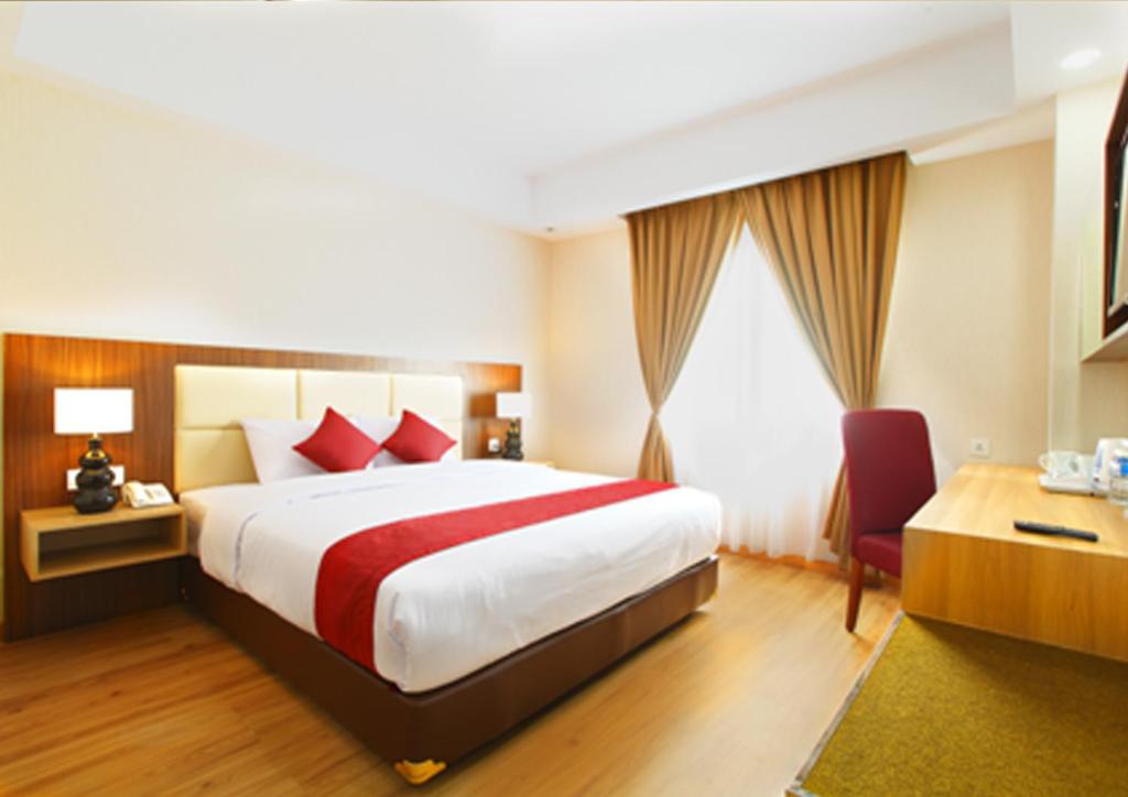 a hotel room with a large bed and a window at Orchardz Hotel Bandara in Tangerang