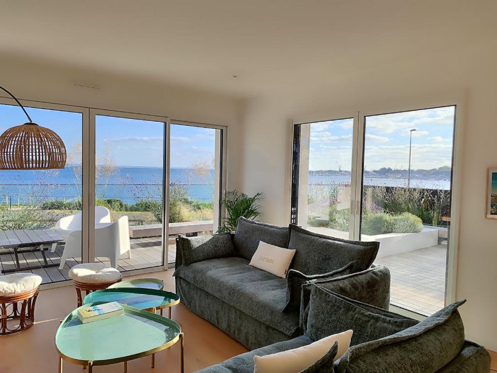 un salon avec un canapé et une vue sur l'océan dans l'établissement Villa vue mer, plage à 30 metres, à Le Relecq-Kerhuon